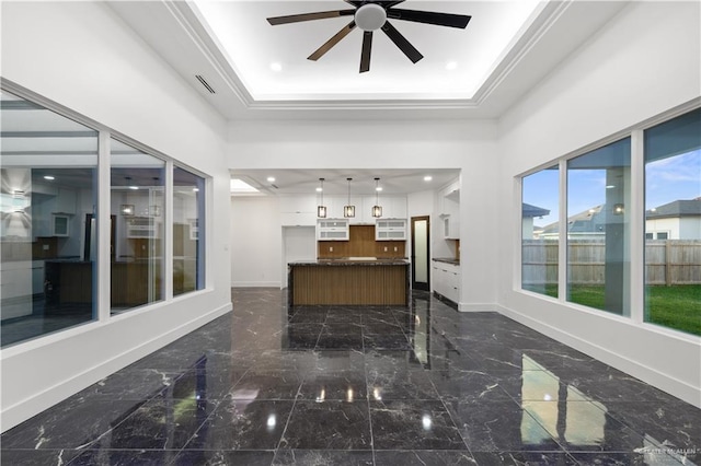 interior space featuring a tray ceiling, ceiling fan, and crown molding