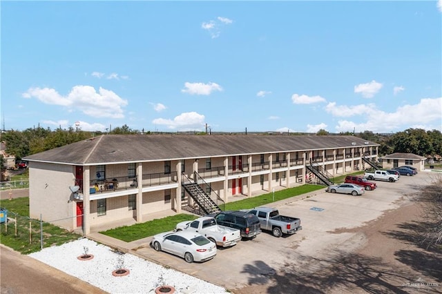 view of building exterior with uncovered parking and stairs