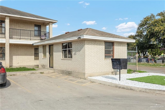 view of side of home featuring uncovered parking and brick siding