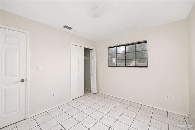 unfurnished bedroom featuring light tile patterned floors, visible vents, and a closet