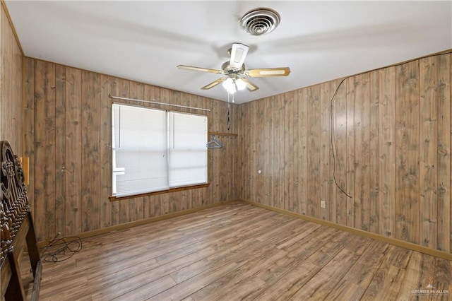 1215 Oak St, Mission, TX 78572 - empty room with wood finished floors, ceiling fan, wood walls, and baseboards