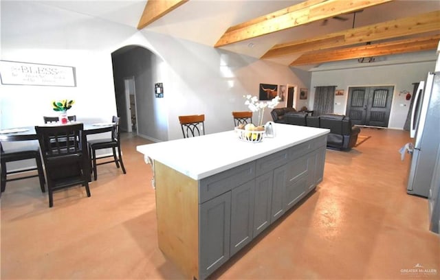 kitchen with lofted ceiling with beams, a center island, gray cabinets, and stainless steel refrigerator