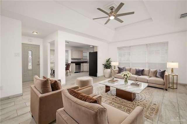 living room featuring ceiling fan and a raised ceiling