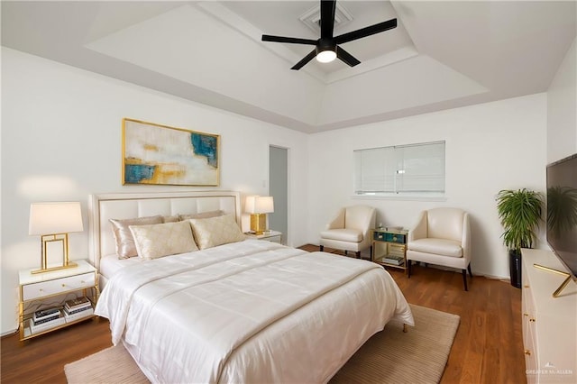 bedroom with dark hardwood / wood-style floors, a raised ceiling, and ceiling fan