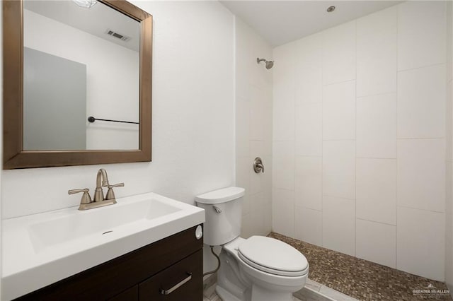 bathroom featuring tiled shower, vanity, and toilet