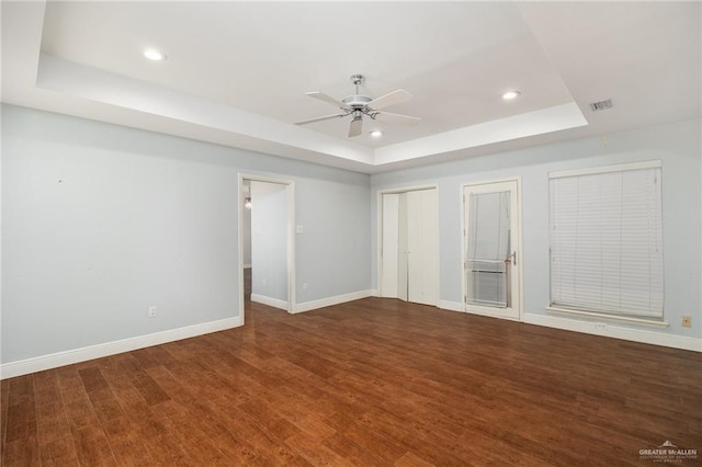 empty room featuring ceiling fan, a raised ceiling, and wood-type flooring