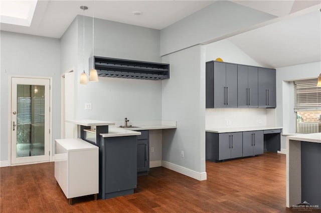 kitchen with kitchen peninsula, hanging light fixtures, dark wood-type flooring, and gray cabinetry