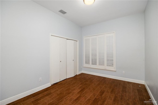 unfurnished bedroom with a closet and dark hardwood / wood-style floors