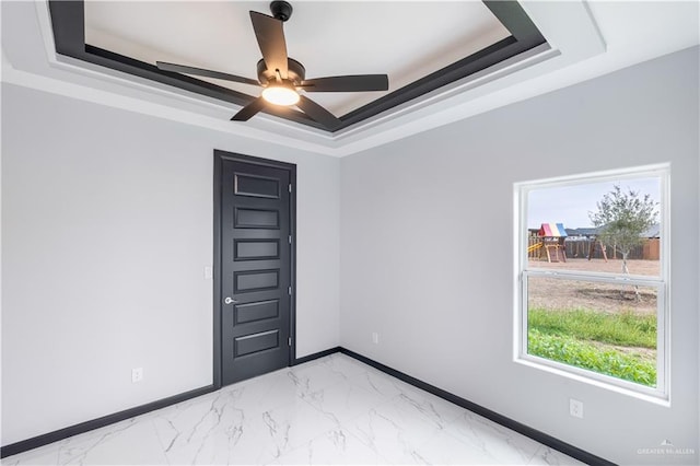 empty room featuring ceiling fan and a tray ceiling