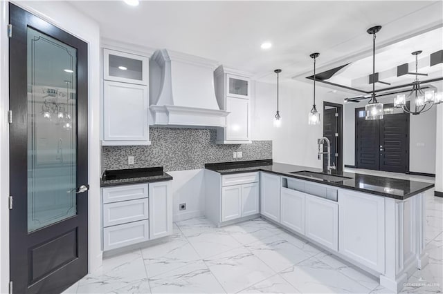 kitchen with white cabinetry, sink, hanging light fixtures, tasteful backsplash, and premium range hood