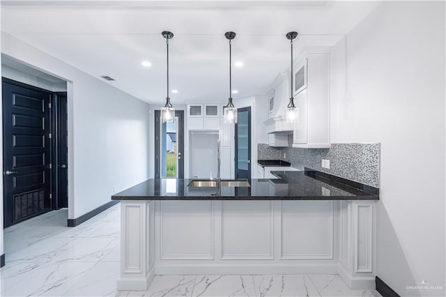 kitchen featuring white cabinetry, tasteful backsplash, kitchen peninsula, dark stone countertops, and decorative light fixtures