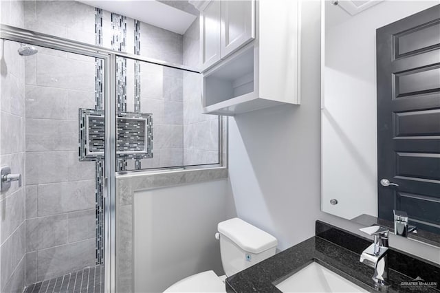 bathroom featuring vanity, a shower with shower door, and toilet