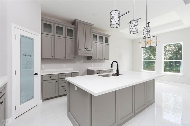 kitchen with gray cabinets, sink, an island with sink, and decorative light fixtures