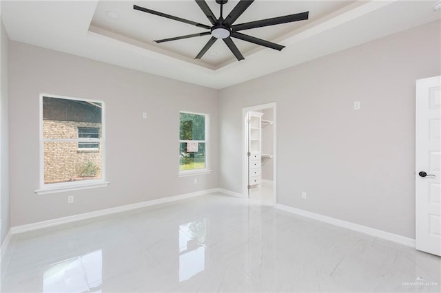 unfurnished room with ceiling fan and a tray ceiling