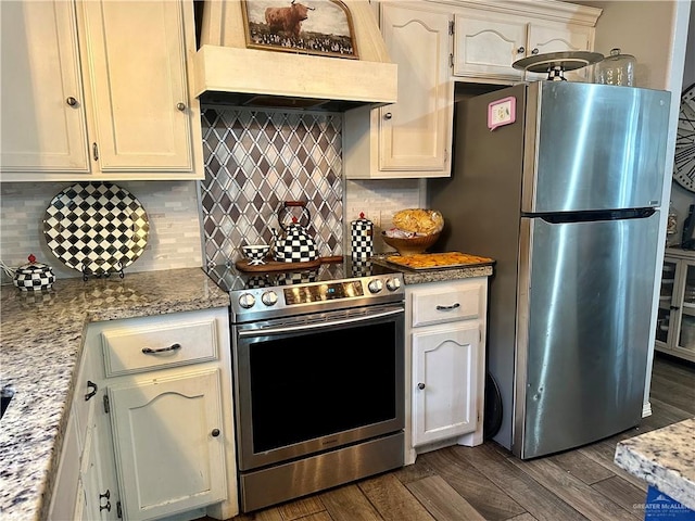 kitchen with backsplash, dark wood-type flooring, appliances with stainless steel finishes, light stone counters, and custom range hood