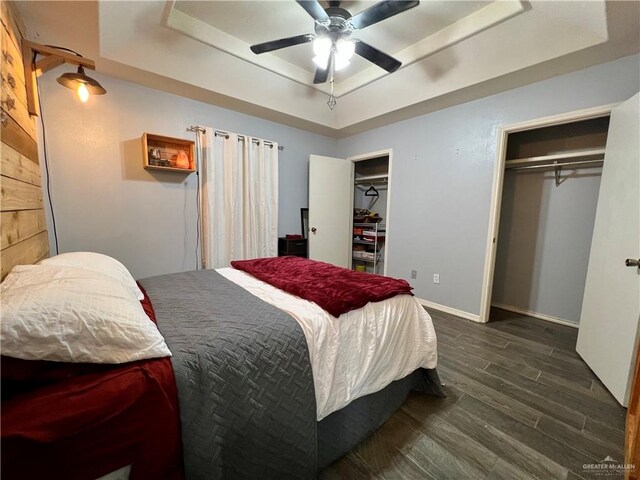 bedroom featuring a raised ceiling, ceiling fan, and dark hardwood / wood-style floors