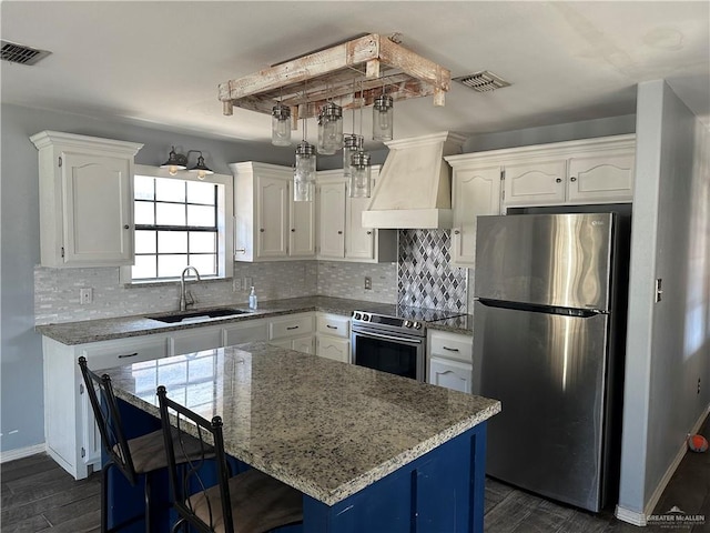 kitchen with sink, a center island, stainless steel appliances, white cabinets, and custom range hood