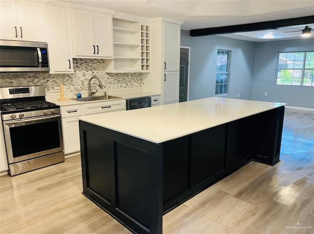kitchen with sink, white cabinetry, stainless steel appliances, and a center island