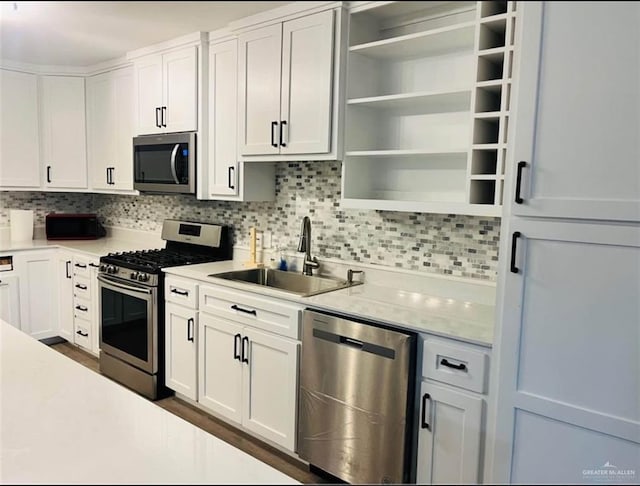 kitchen with appliances with stainless steel finishes, light stone counters, white cabinets, decorative backsplash, and sink