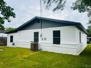 rear view of property featuring a lawn and cooling unit