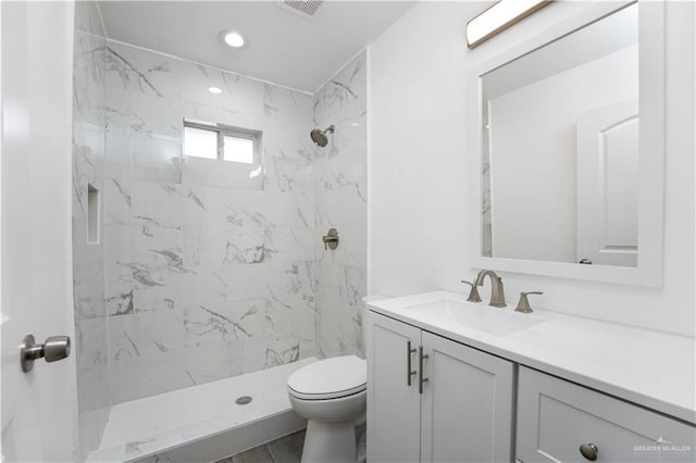 bathroom with vanity, toilet, and tiled shower