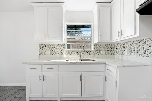 kitchen with ventilation hood, backsplash, white cabinetry, and sink