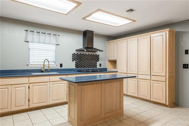 kitchen featuring a kitchen island, light brown cabinetry, sink, stainless steel gas cooktop, and wall chimney exhaust hood