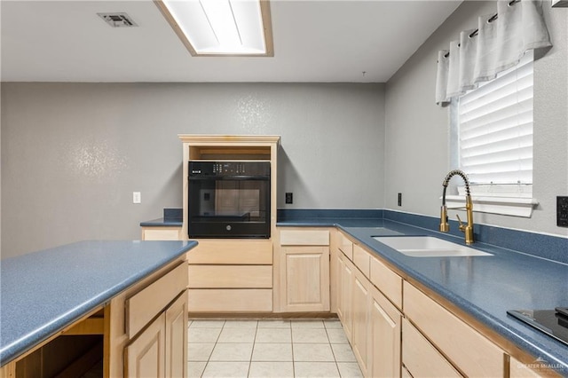 kitchen featuring light tile patterned floors, oven, sink, and light brown cabinets