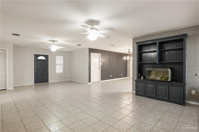 unfurnished living room with light tile patterned floors, ceiling fan with notable chandelier, and wooden walls