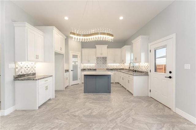 1711 Lago Delton, Edinburg, TX 78542 - kitchen featuring light marble finish flooring, decorative backsplash, a sink, white cabinetry, and a kitchen island