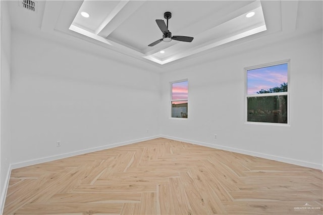 spare room with ceiling fan, a tray ceiling, and light parquet floors