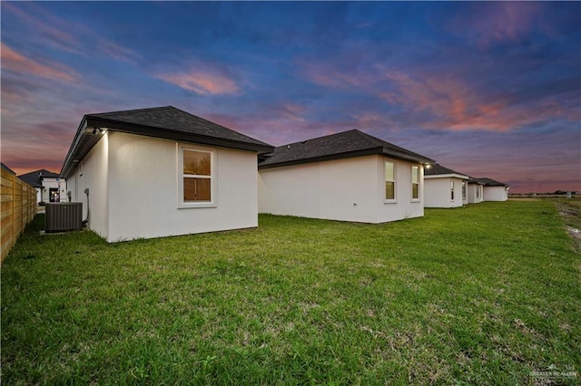 property exterior at dusk with a yard and central AC