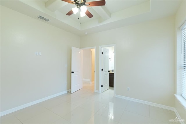 unfurnished bedroom with light tile patterned floors, baseboards, visible vents, a raised ceiling, and a ceiling fan