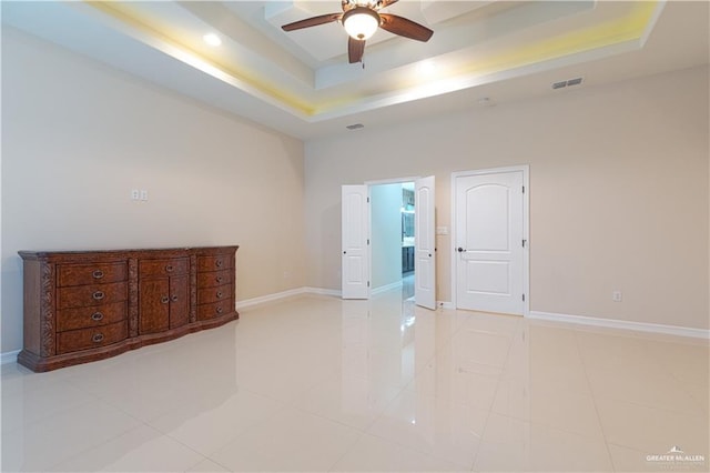 empty room featuring baseboards, visible vents, a raised ceiling, and a ceiling fan