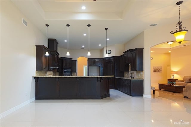 kitchen featuring arched walkways, a peninsula, a sink, and wall oven