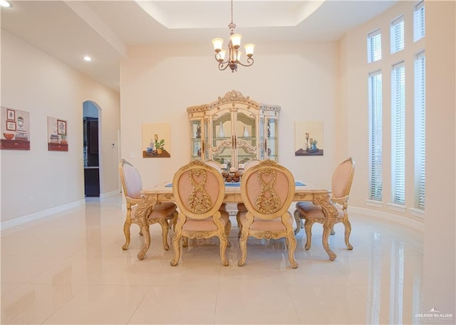 tiled dining room with arched walkways, a chandelier, recessed lighting, baseboards, and a raised ceiling