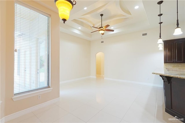 unfurnished living room featuring arched walkways, ceiling fan, visible vents, baseboards, and a raised ceiling