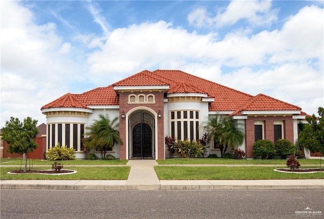 mediterranean / spanish house with a tiled roof, a front lawn, and stucco siding