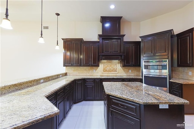 kitchen with stainless steel double oven, dark brown cabinets, backsplash, light stone countertops, and pendant lighting