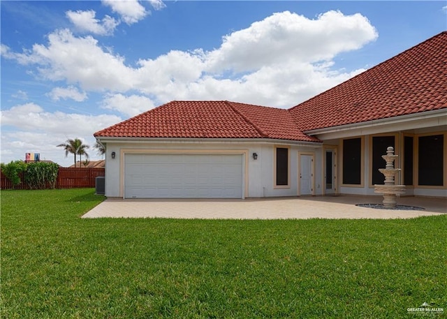 exterior space featuring a lawn, a tiled roof, an attached garage, and fence