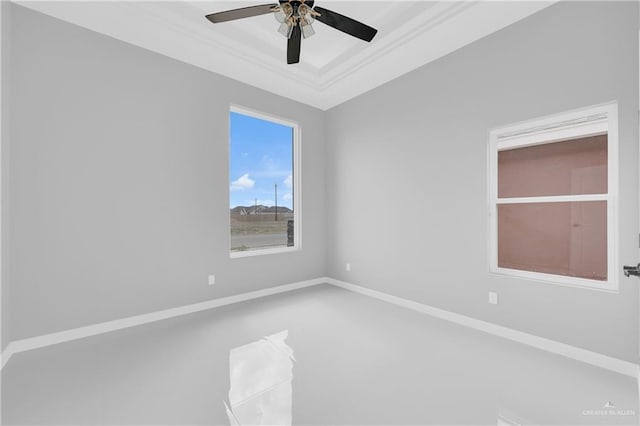 empty room featuring a tray ceiling, crown molding, baseboards, and a ceiling fan