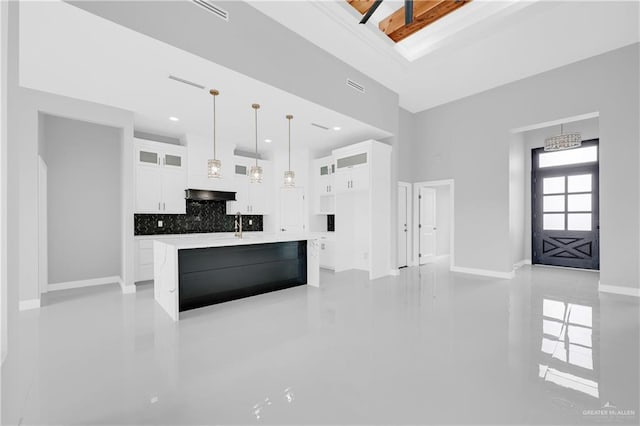 kitchen featuring decorative backsplash, white cabinets, glass insert cabinets, light countertops, and under cabinet range hood