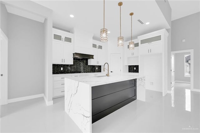 kitchen featuring pendant lighting, decorative backsplash, white cabinets, a sink, and light stone countertops