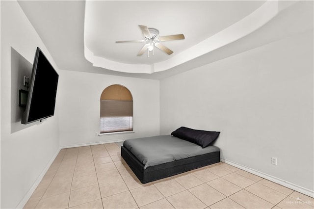 bedroom with a tray ceiling, ceiling fan, and light tile patterned floors