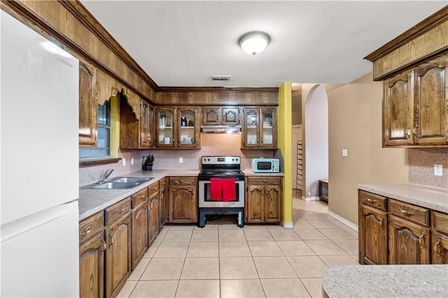 kitchen with decorative backsplash, light tile patterned floors, white appliances, and sink