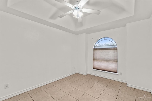 spare room featuring ceiling fan, light tile patterned flooring, and a raised ceiling