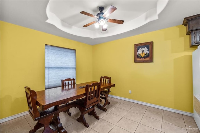 tiled dining space featuring ceiling fan and a raised ceiling