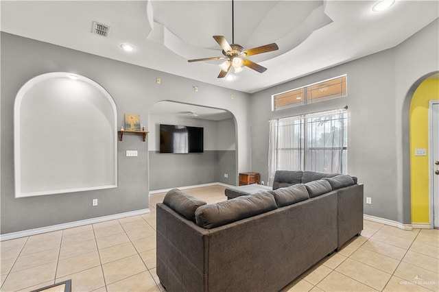 tiled living room featuring a tray ceiling and ceiling fan