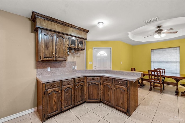 kitchen with kitchen peninsula, tasteful backsplash, dark brown cabinetry, ceiling fan, and light tile patterned flooring