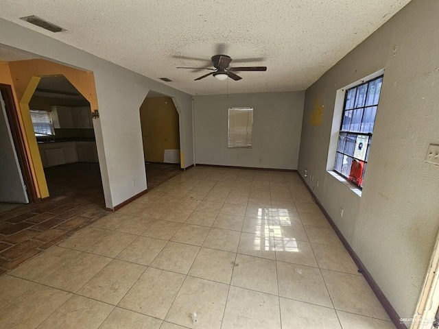 unfurnished room with ceiling fan, a textured ceiling, and light tile patterned floors